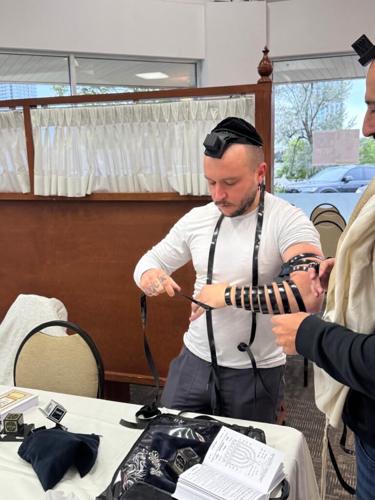 Wrapping tefillin at the Centre, helped by the rabbi