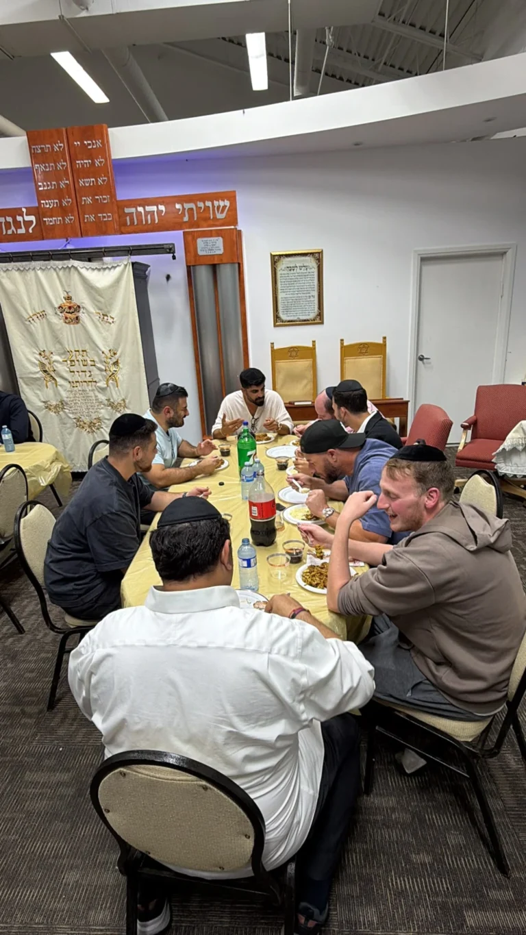 Guests talking over dinner at a table in front of the aron kodesh