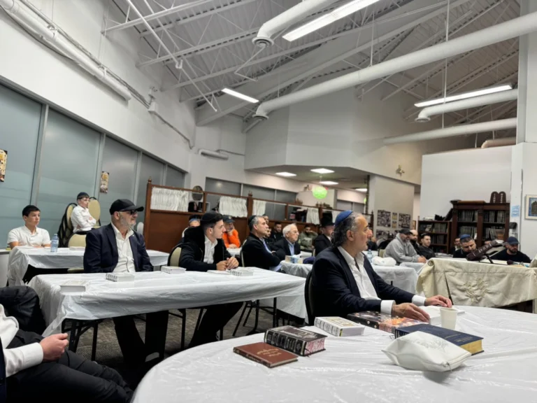 Men seated at the tables listening to a shiur in the main hall