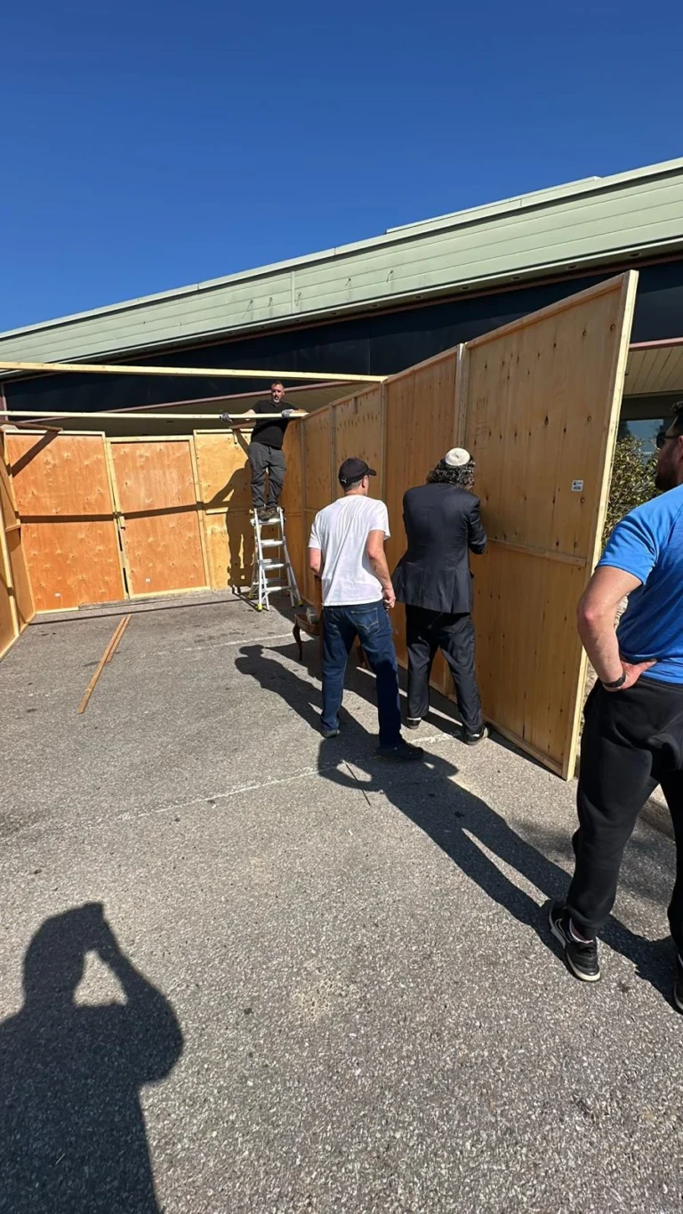 Volunteers building the sukkah walls in the daytime