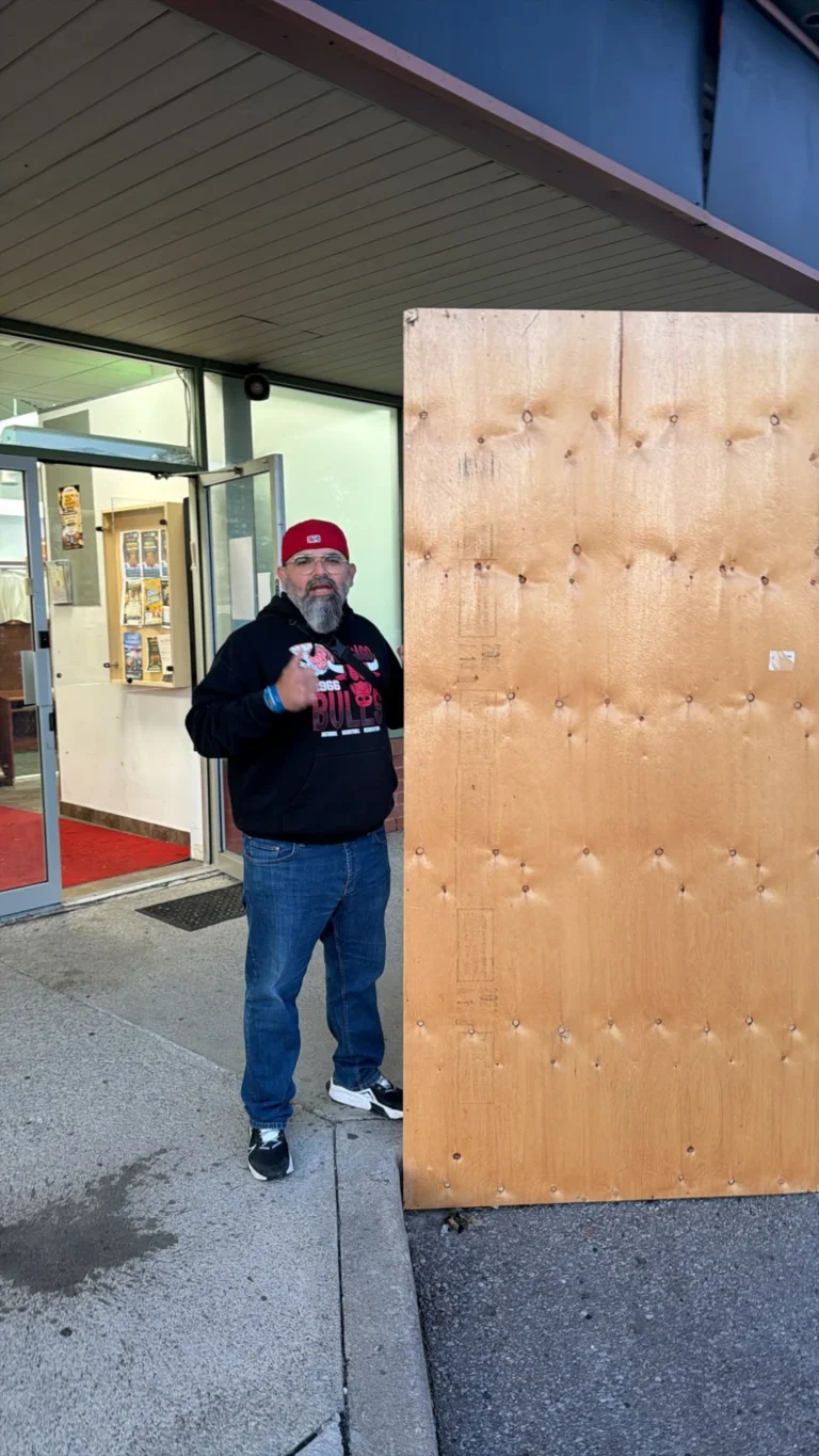 A volunteer giving a thumbs-up beside a sukkah panel at the Centre's door