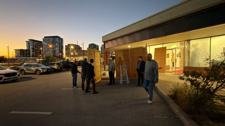Volunteers carrying sukkah panels across the parking lot at sunset